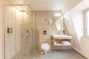 a bathroom with a shower and a toilet and a sink at Hotel Saint Augustin in Strasbourg