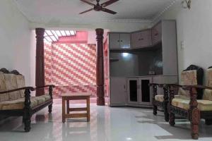 a living room with chairs and a ceiling fan at Cheerful home in Mysore