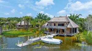 a house on the water with a boat in the water at LE VILLAGE D'HÉLÈNE - Natura Resort in Ouidah