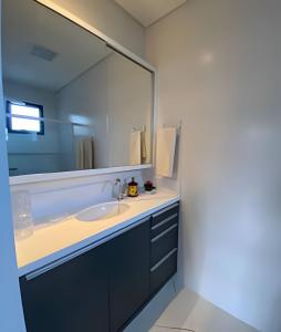 Aconchegante Casa 3 suites no Atiradores في جوينفيل: حمام مع حوض ومرآة كبيرة