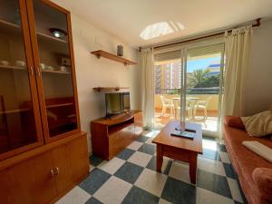 ein Wohnzimmer mit einem Sofa, einem TV und einem Tisch in der Unterkunft Apartamentos Bonaire 3000 in Oropesa del Mar