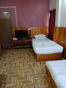 a hotel room with two beds and a flat screen tv at Tashi Yarphel in Pajo
