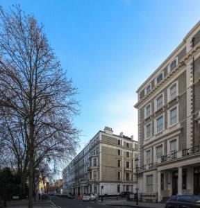 een straat met twee hoge gebouwen en een boom bij Cleveland Residences Kensington in Londen