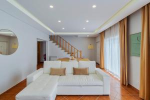 a living room with a white couch and stairs at Casa Rosa in Quinta do Conde +21 photos