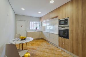 a large kitchen with a table and a microwave at Casa Rosa in Quinta do Conde