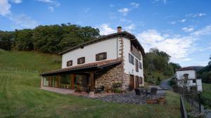 una casa en una colina con un campo de hierba en Olagaraia - Adults Only, en Etxalar