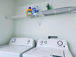a laundry room with two washing machines and a shelf at Urban Oasis Getaway in Jacksonville