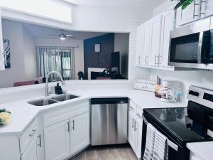 a kitchen with white cabinets and a stainless steel sink at Urban Oasis Getaway in Jacksonville