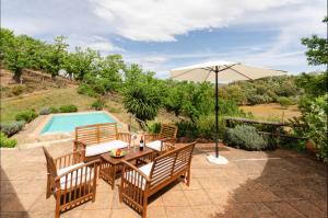 een patio met een tafel, een parasol en een zwembad bij Finca el Moro - Casita del Castañar in Aracena