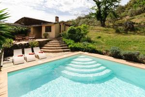 een zwembad met twee stoelen en een huis bij Finca el Moro - Casita del Castañar in Aracena