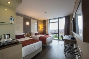 a hotel room with two beds and a desk at Ramada Encore Istanbul Bayrampasa in Istanbul