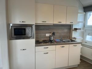 a kitchen with white cabinets and a microwave and a sink at Sint-Amandstraat studio B4 in Ghent