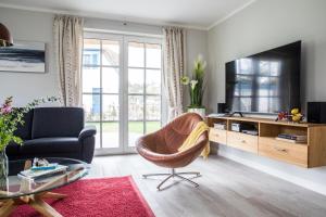 a living room with a chair and a television at Ferienhaus Seeadler 9 in Fuhlendorf