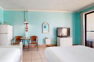 a room with two beds and a tv and a table at Pirates Bay A210 in Fort Walton Beach