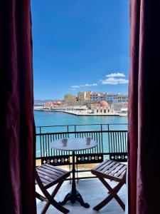 a table and chairs on a balcony with a view of the water at Erietta Suites in Chania Town