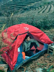 a man sitting inside of a red tent at Zhangjiajie National Forest Park Camping in Zhangjiajie