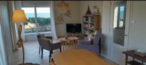 uma sala de estar com uma mesa e cadeiras e uma televisão em Vue exceptionnelle en front de mer, 8 personnes em Ver-sur-Mer