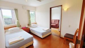 a bedroom with two beds and a mirror and a chair at Pension and Restaurant La Collina in Nakafurano