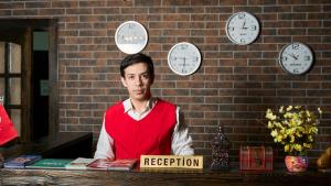 a man sitting at a table with clocks on the wall at Xan Hotel in Baku