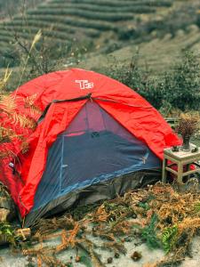 Zhangjiajie National Forest Park Camping في تشانغجياجيه: خيمة حمراء وسوداء جالسة على ميدان