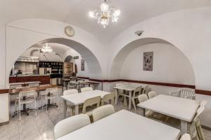 ローマにあるホテル アルタヴィラ 9の白いテーブルと白い椅子が備わるレストラン
