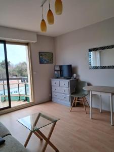 Una sala de estar con una mesa de cristal y un televisor. en Le Sylvania, en Saint-Georges-de-Didonne