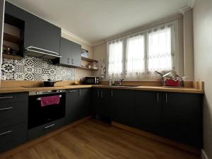 een keuken met zwarte kasten, een wastafel en een raam bij Familial Apartment - Troyes in Troyes