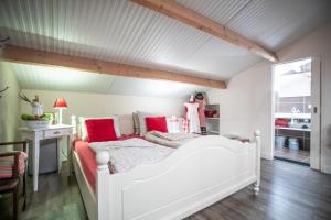 een slaapkamer met een wit bed met rode kussens bij de Huttert Opkamer in Luttenberg