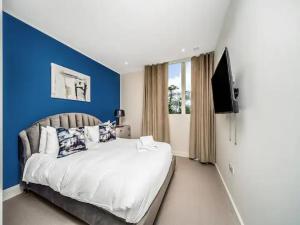 a bedroom with a large bed with a blue wall at Pass the Keys Modern 2-BR Penthouse Oasis Ideal for Business Family and Group Retreats in Trendy Fulham in London