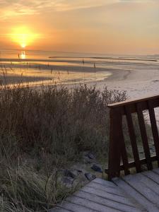 ヴェスターラントにあるPelzer Haus Atlantikの夕日のビーチに座るベンチ