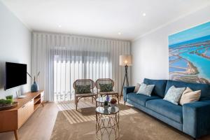 een woonkamer met een blauwe bank en een tv bij Apartamento Beira Mar - 1º Direito in Tavira
