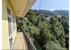 un balcone di una casa con vista sugli alberi di Goroomgo Homestay Sukh Dham Shimla - Homestay Like Home Feeling Mountain View a Shimla