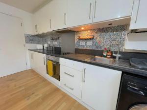 a kitchen with white cabinets and a sink at Ground Floor Flat On Bath Road! in Cranford