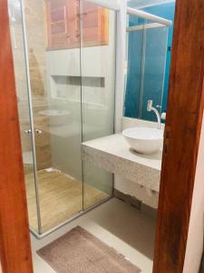 a bathroom with a sink and a glass shower at Casa Flora Canoa Quebrada in Canoa Quebrada