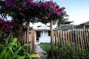 a wooden fence with a tree with purple flowers at Casa Flora Canoa Quebrada in Canoa Quebrada