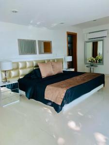 1 dormitorio con 1 cama grande, 2 mesas y 2 lámparas en Casa VIP en Cartagena cerca a la playa, en Cartagena de Indias