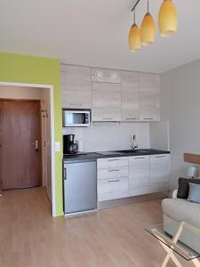 una cocina con armarios blancos y un sofá en una habitación en Le Sylvania en Saint-Georges-de-Didonne
