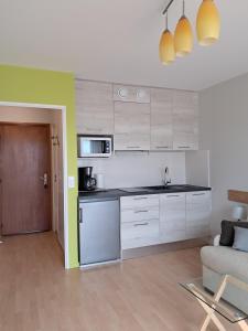 una cocina con armarios blancos y un sofá en una habitación en Le Sylvania, en Saint-Georges-de-Didonne
