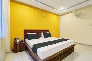 a bedroom with a bed with a yellow wall at OYO Dreams Comforts Lodging and Boarding in Bangalore