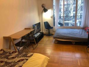 a room with a desk and a bed and a deskablish at Grand appartement proche métro in Paris