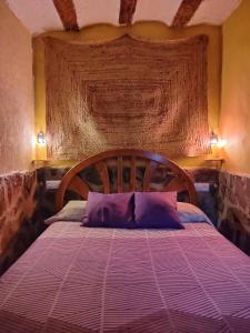 アルカラ・デル・フカルにあるCasa Rural con Jacuzzi Paraíso del Júcarのベッドルーム1室(紫色の枕が付いたベッド1台付)