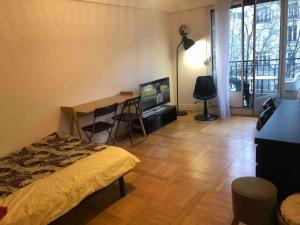 a room with a bed and a desk and a television at Grand appartement proche métro in Paris