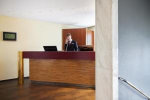 a woman is standing at a desk with a laptop at Hotel Central Hamburg in Hamburg