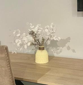 a yellow vase with flowers in it on a table at Le SerenityAppart Suresnes in Suresnes