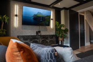 a living room with a couch and a tv on the wall at Luxury Worcester Townhouse - Free Parking in Henwick