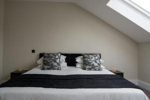 una camera da letto con un grande letto con cuscini bianchi e neri di Luxury Worcester Townhouse - Free Parking a Henwick