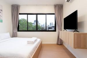 a bedroom with a bed and a flat screen tv at Townhouse in Pratunam Bangkok in Bangkok