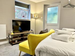 a bedroom with a yellow chair and a television at Firs Nook with Parking in Stillington