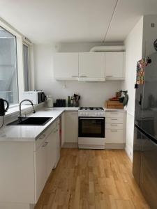 a white kitchen with white appliances and wooden floors at Modern apartment in Ørestad in Copenhagen