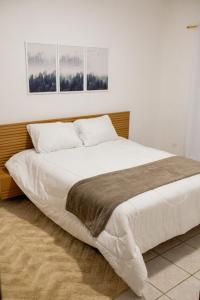 a large bed in a bedroom with three pictures on the wall at Respiro na Serra, casa no coração de Gonçalves in Gonçalves